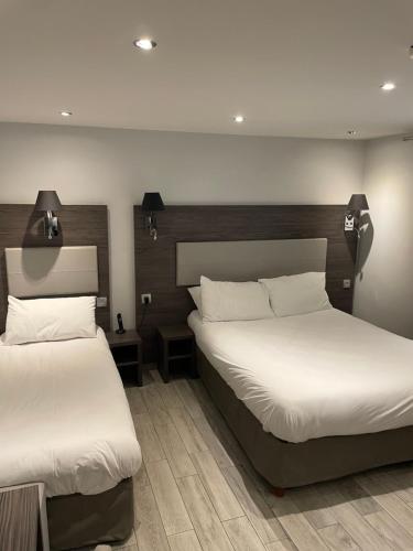 two beds in a hotel room with white sheets at Mary's Hotel République in Paris