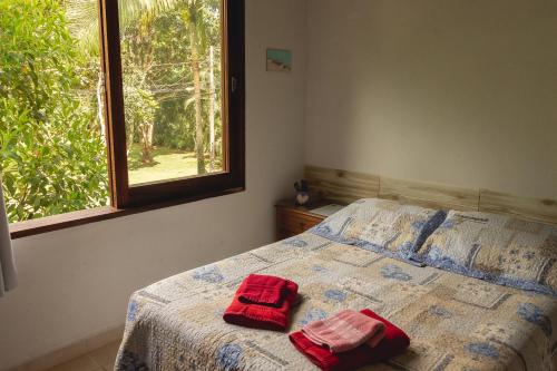 a bedroom with a bed with two red towels on it at Suites surf house itamambuca in Ubatuba