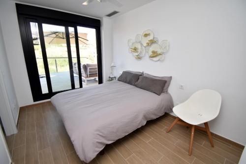 a bedroom with a white bed and a white chair at 5056 Apartamento Nuba Javea in Jávea