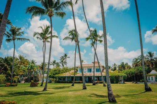 a group of palm trees in front of a house at Casa Brasileira - Hotel Galeria in Pôrto de Pedras