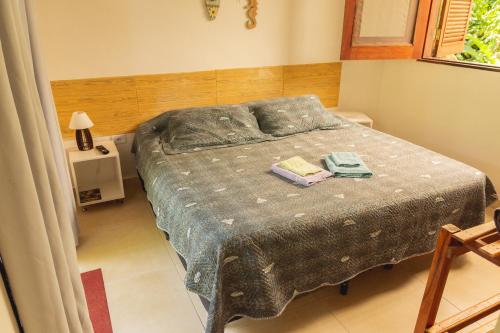 a bedroom with a bed with two towels on it at Suites surf house itamambuca in Ubatuba