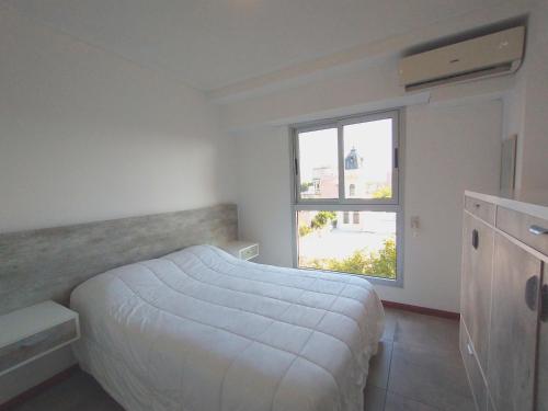 Habitación blanca con cama y ventana en Depto Alem en Rosario