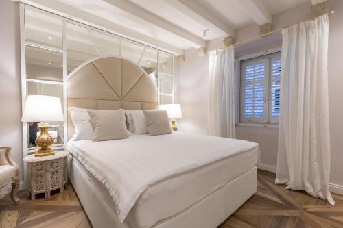 a white bedroom with a large bed and a window at St. Joseph's in Dubrovnik