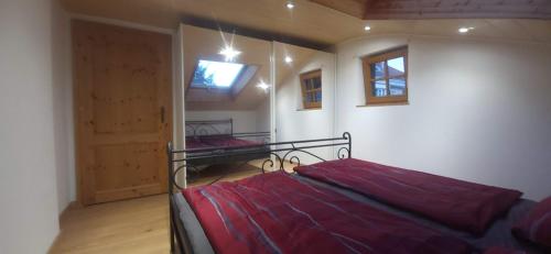 1 dormitorio con 1 cama con manta roja y puerta en Sigrids Ferienwohnung Bad Tölz, en Bad Tölz