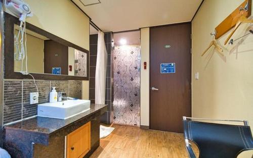 een badkamer met een wastafel, een spiegel en een douche bij Chakan Hotel in Gunsan
