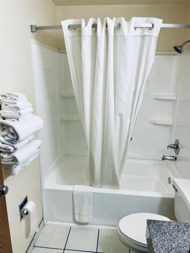 a bathroom with a white tub and a shower curtain at Super 8 by Wyndham Corbin KY in Corbin