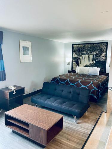 a living room with a bed and a blue couch at Super 8 by Wyndham Corbin KY in Corbin