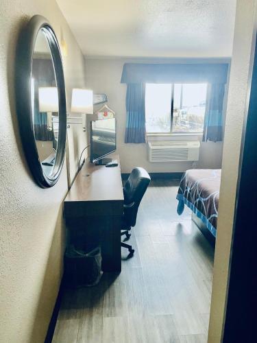 a hotel room with a desk and a bed and a mirror at Super 8 by Wyndham Corbin KY in Corbin
