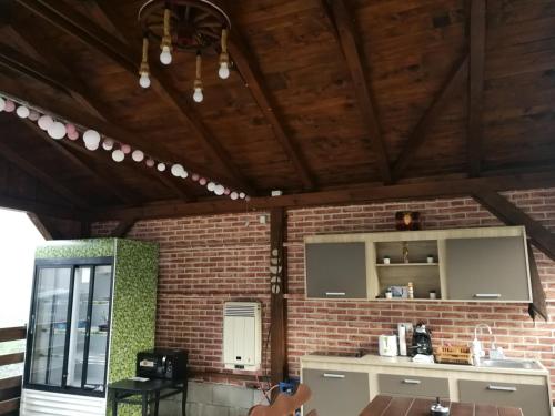 a kitchen with a brick wall and wooden ceiling at Căsuțe Zăvoi Bulz in Bulz