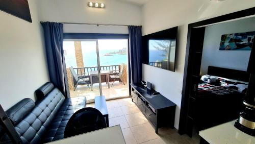 a living room with a couch and a view of the ocean at DELUXE SeaView-SUNSETS !TRANSFE-R inc! POOL,2AirCond,2TV65",600Mb Dishwasher,,2 BEACHes,ANFI-view in Patalavaca
