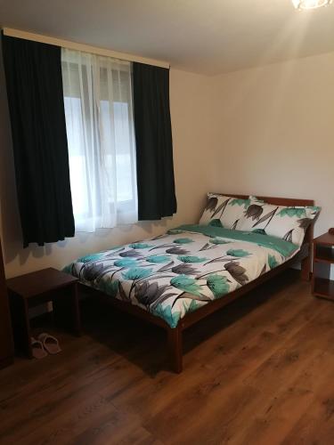 a bedroom with a bed and a window with black curtains at Căsuțe Zăvoi Bulz in Bulz