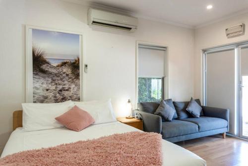 a bedroom with a bed and a blue couch at Gawler Townhouses 1b in Gawler