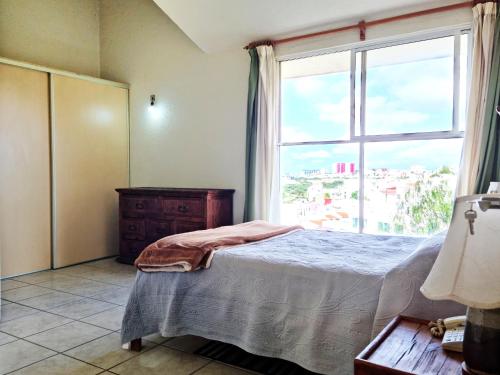 a bedroom with a bed and a large window at Departamento Vintage Querétaro in La Cañada