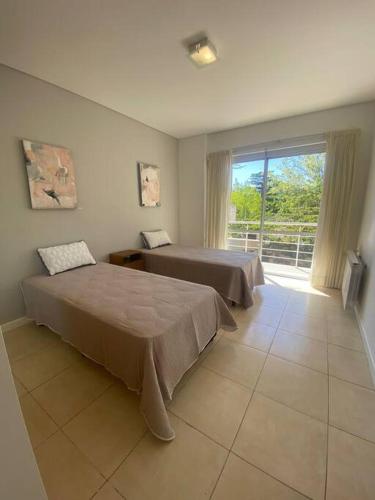 1 dormitorio con 2 camas y ventana grande en departamento 2 dormitorios 2 baños en Mendoza