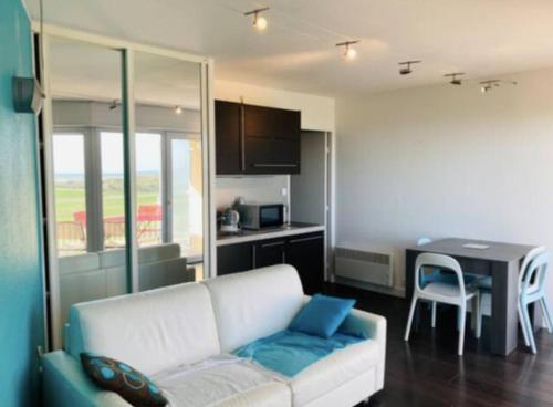 een woonkamer met een bank en een keuken bij Studio vue mer avec piscine in Saint-Jean-de-Monts