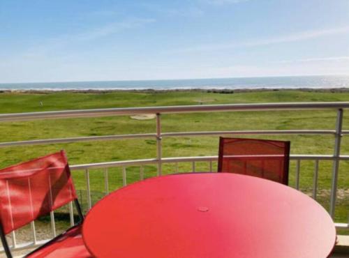 een rode tafel en stoelen op een balkon met uitzicht op de oceaan bij Studio vue mer avec piscine in Saint-Jean-de-Monts