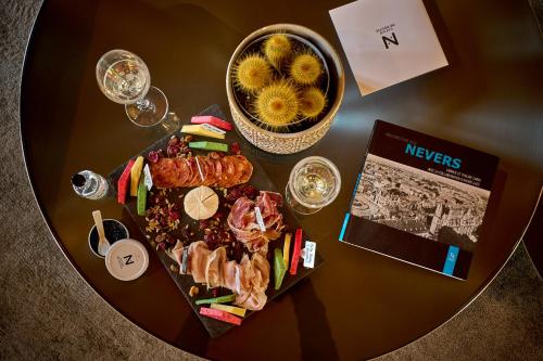 a table with a plate of food and a basket of flowers at La Chapelle, Les Suites du Palais, l'unique 5 étoiles de Nevers, Suite d'Exception, by PRIMO C0NCIERGERIE in Nevers