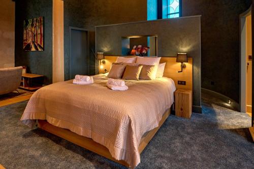 a bedroom with a large bed with two pink pillows at La Chapelle, Les Suites du Palais, l'unique 5 étoiles de Nevers, Suite d'Exception, by PRIMO C0NCIERGERIE in Nevers