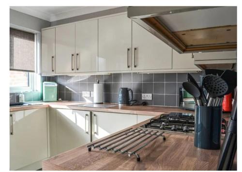 La cuisine est équipée de placards blancs et d'un four avec plaques de cuisson. dans l'établissement The Barbers, à Beverley