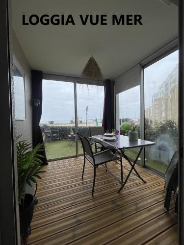 une table et une chaise dans une chambre avec une grande fenêtre dans l'établissement Magnifique appartement vue Mer / Terrasse et Parking privée, à Pornichet