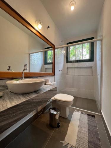 a bathroom with a sink and a toilet and a mirror at Cama e Café Tiradentes in Tiradentes