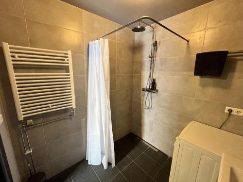 a shower with a white shower curtain in a bathroom at Bridge Apartment in Egilsstadir