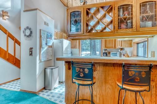 uma cozinha com um balcão e duas cadeiras num bar em The Huckleberry Cabin em Sunriver