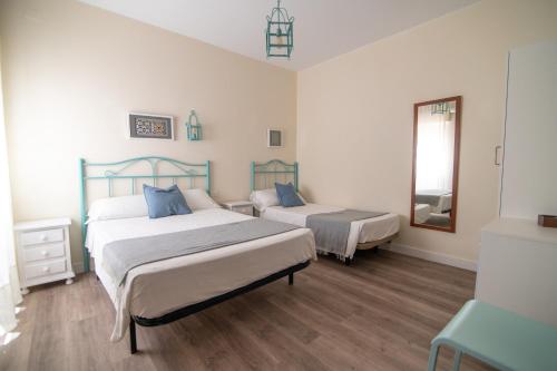 a bedroom with two beds and a mirror at Hostal Andalucía in Chipiona