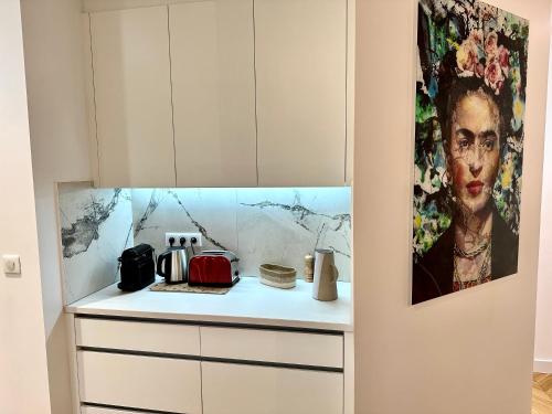 une cuisine avec des placards blancs et un tableau mural. dans l'établissement Bel Appartement avec parking au coeur de Reims, à Reims