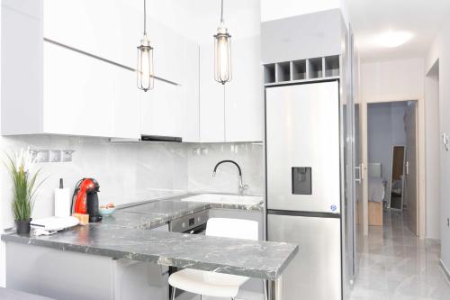cocina con armarios blancos y nevera de acero inoxidable en Luxury Apartment in Thessaloniki Centre en Tesalónica