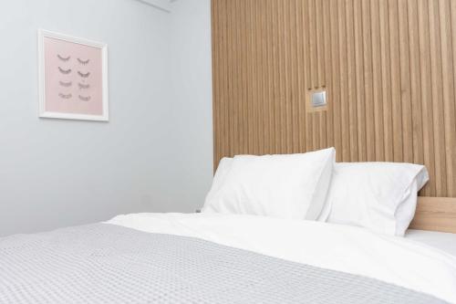 Schlafzimmer mit einem Bett mit weißer Bettwäsche und Kissen in der Unterkunft Luxury Apartment in Thessaloniki Centre in Thessaloniki
