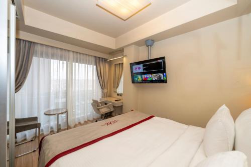 a hotel room with a bed and a tv on the wall at Ramada By Wyndham Istanbul Pera Taksim in Istanbul