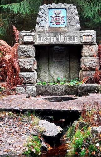 a stone fountain with a sign for a garden at Hotel Garni Schloß Schönberg in Bad Brambach