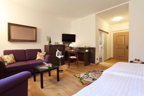 a hotel room with a bed and a couch and a desk at Hotel Garni Schloß Schönberg in Bad Brambach