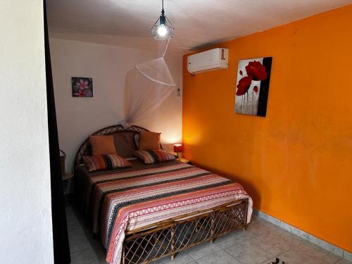 a bedroom with a bed with an orange wall at L'EXOTIK 2 in Les Abymes