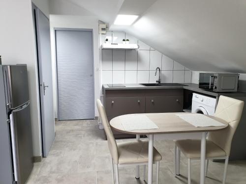 une cuisine avec une table et des chaises dans une pièce dans l'établissement VittelLoc 4 Studios proches parc thermal et centre ville au calme, à Vittel