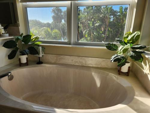 eine große weiße Badewanne im Badezimmer mit zwei Topfpflanzen in der Unterkunft Renovated Spacious Beach House-Steps from the Beach! in Fort Pierce
