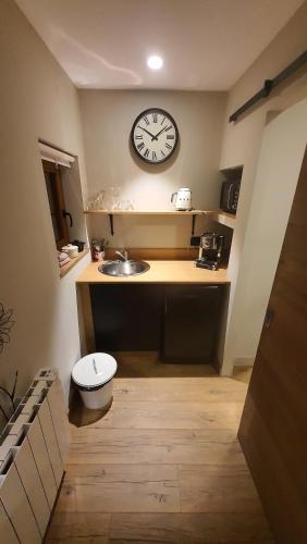 uma casa de banho com um lavatório e um relógio na parede em Votre chez vous em Bergheim