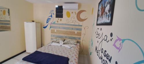 a small bedroom with a bed and a wall with graffiti at Pousada João de Barro in Camaçari
