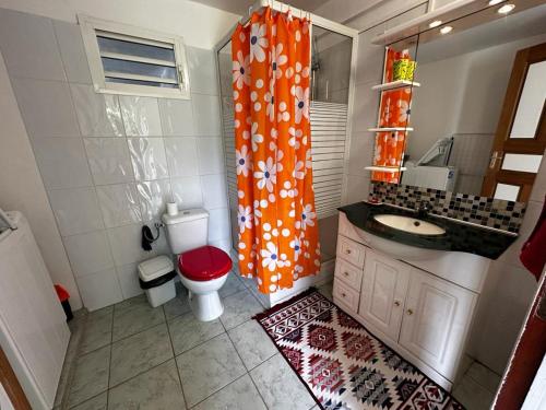 uma casa de banho com um WC e uma cortina de chuveiro laranja em L'EXOTIK 2 em Les Abymes