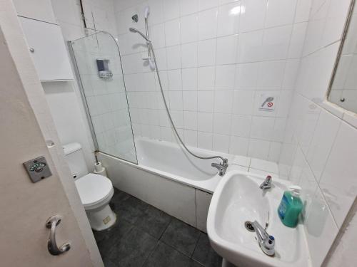 een badkamer met een wastafel, een toilet en een douche bij City Budget Guesthouse in Londen