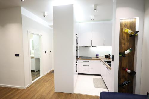 a kitchen with white cabinets and a wooden door at Apartman Morava in Čačak