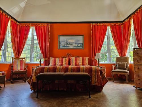 a bedroom with a bed with orange walls and windows at Spicy Hill Villa in Port Antonio