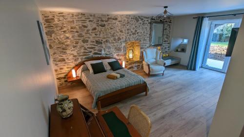 - une chambre avec un lit et un mur en pierre dans l'établissement La Salabertie, à Bagnac