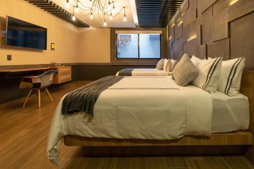 1 dormitorio con 2 camas, escritorio y TV en Hotel Patio Santiago, en Querétaro