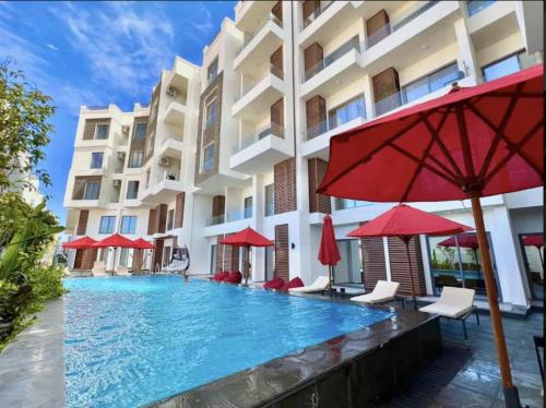 a pool in front of a building with red umbrellas at Fabulous Penthouse seaview wifi in Boutique resort in Hurghada