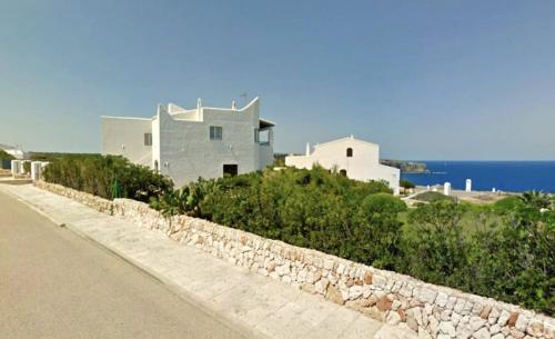 a house on a hill next to a road at Villa MORELL in Cala Morell