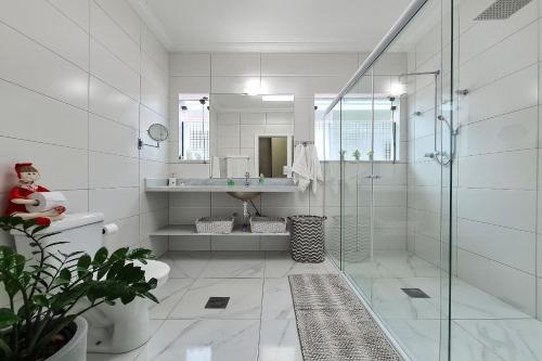 a bathroom with a glass shower and a sink at Casa com piscina e churrasqueira no Guarujá in Guarujá