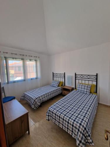 - une chambre avec 2 lits, une table et des fenêtres dans l'établissement TaraVilla, à Tarajalejo