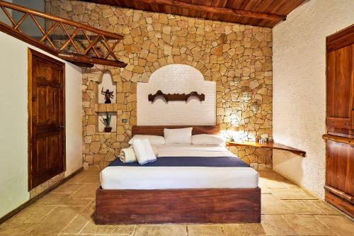 a bedroom with a bed and a stone wall at Villa Havana in Mal País